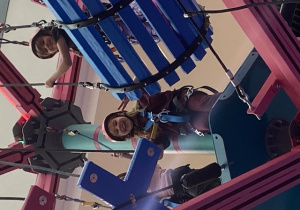 Uczennice na torze przeszkód na wysokości ubrane w profesjonalne stroje do wspinaczki.