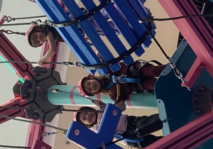 Uczennice na torze przeszkód na wysokości ubrane w profesjonalne stroje do wspinaczki.