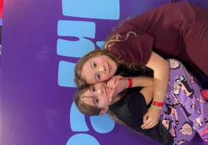 Dwie uczennice pozują do zdjęcia przytulając się do siebie.