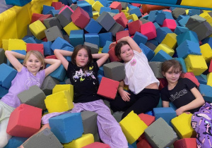 Cztery uczennice w basenie z kolorowymi gąbkami.