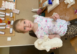 Uczennica prezentuje pingwina wykonywanego z gipsowego bandaża.