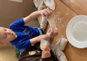 Chłopiec moczy bandaż w wodzie.