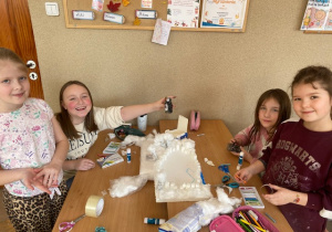 Dziewczynki budują zagrodę pingwinów ze styropianu i kostek cukru.
