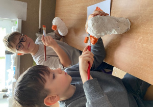 Chłopcy malują pingwiny farbą.