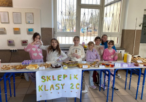 Dziewczynki z klasy 2 c przy swoich stanowiskach pracy jako sprzedawcy.