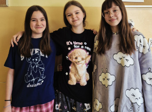 Dziewczynki z klasy 6 pozujące do zdjęcia w piżamach na szkolnym korytarzu.