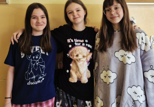 Dziewczynki z klasy 6 pozujące do zdjęcia w piżamach na szkolnym korytarzu.