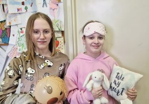 Dwie dziewczynki z klasy 5 pozujące do zdjęcia w piżamach.