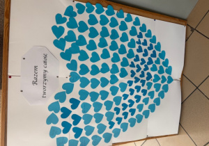 Plakat pt. "Razem tworzymy całość" w formie błękitnego serca utworzonego z małych serduszek, na których uczniowie mogą wpisywać hasla motywujące kolegów w spektrum autyzmu.