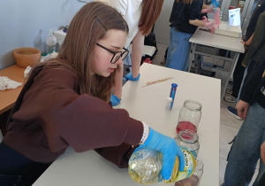 Uczennica klasy 7C nalewa olej do zlewki celem wykonania doświadczenia fizyko-chemicznego lampa lawa.