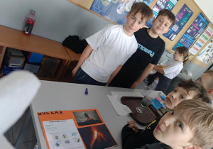 Dwóch uczniów klasy 7B prezentuje eksperyment wulkan młodszym kolegom.