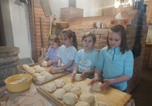 Uczennice wyrabiają rękoma ciasto na chleb.