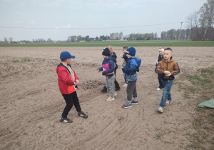 Uczniowie podczas siania ziarna na polu.
