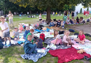 Wspólny odpoczynek i piknikowanie na kocach jako jeden z elementów swobodnej zabawy w dniu święta uczniów.