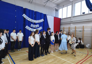 Uczniowie klas y 8 b odbierają świadectwa z wyróżnieniami.