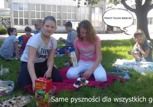 Uczniowie jedzą przygotowane słodkości podczas pikniku szkolnego