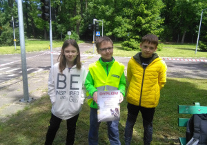 Trzej uczniowie pokazują zdobyty w konkursie dyplom