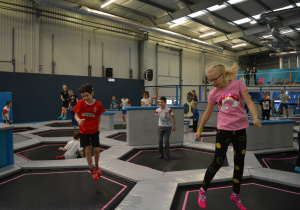 Uczniowie skaczą na małych trampolinach w parku trampolin Saltos