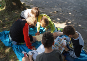 Grupka uczniów z klas młodszych pokazuje kolegom najciekawsze fragmenty swoich książek