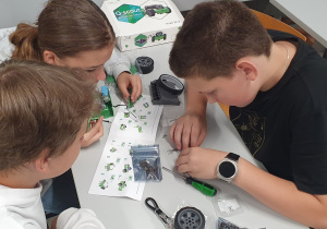 Troje uczniów montuje robota