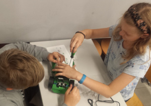 Dwoje uczniów montuje robota