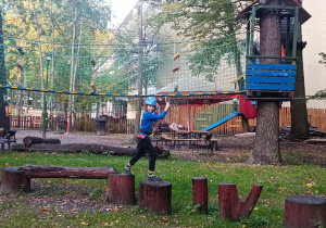 Uczeń przechodzi po drewnianych pniach wkopanych w ziemię