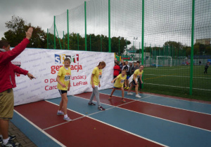 Czworo uczniów w żółtych strojach sportowych na starcie biegu.