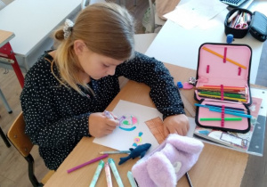 Uczeń wykonuje pracę plastyczną z wykorzystaniem kredek techniką połącz kropki