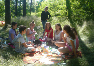 Uczniowie siedzą na kocu podczas pikniku klasowego