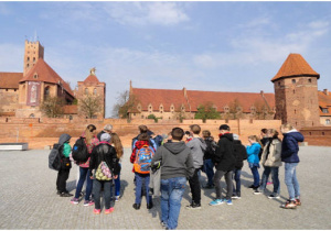 Uczniowie pozują na tle murów starego miasta w Toruniu