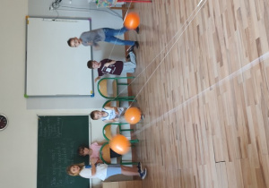 Pięcioro uczniów klasy IIB patrzy na pędzące po sznurkowym torze balony.