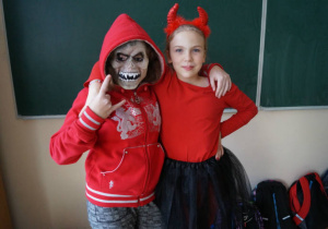 Dwójka uczniów przebranych za potwora i diabła pozuje podczas dyskoteki halloweenowej