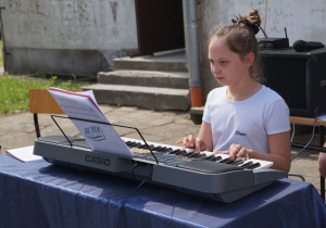 Uczennica gra na keyboardzie podczas festynu szkolnego