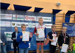 Czterej zwycięzcy zawodów sportowych z dyplomami i medalami na podium