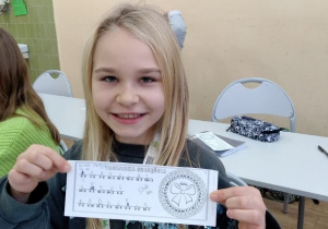 Uczennica 4b prezentuje do zdjęcia rozkodowaną „Tabliczkę Szczęścia”