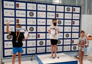 Trzech zawodników stoi na podium i odbiera dyplomy i medalae