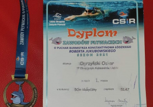 Dyplom uznania i medal zdobyty przez Oskara w zawodach pływackich.