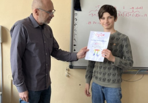 Nauczyciel matematyki Robert Pietrusiak wręcza dyplom zwycięzcy konkursu