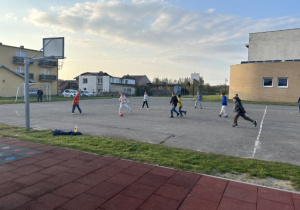 Uczniowie klasy 5b na boisku, grający w piłkę nożną.