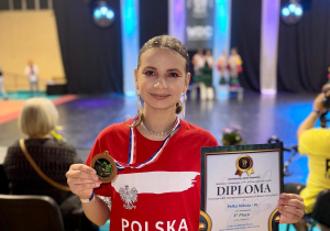 Nikola ubrana w czerwona koszulkę z napisem Polska prezentuje zdobyty medal i dyplom.