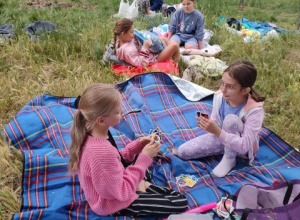 Sześć uczennic siedzi na kocach i gra w przyniesione gry.