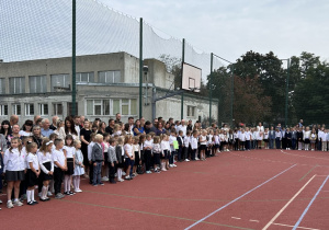 Uczniowie klas pierwszych na boisku szkolnym podczas uroczystości rozpoczęcia roku szkolnego