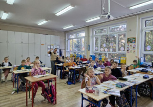 Nauczycielka Anna Gawlińska oraz uczniowie z klasy 1 a prezentują kolorowe stroj.