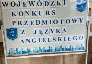 Biała tablica z niebieskim napisem: Wojewódzki Konkurs Przedmiotowy z Języka Angielskiego.