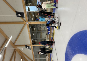 Uczniowie grają rozgrywki w mini curling.