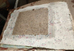 3.Mokry papier czerpany, położony na kwiecistej tkaninie do wyschnięcia.