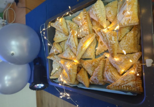 Francuskie ciasteczka z wróżbami na tle niebieskich balonów.